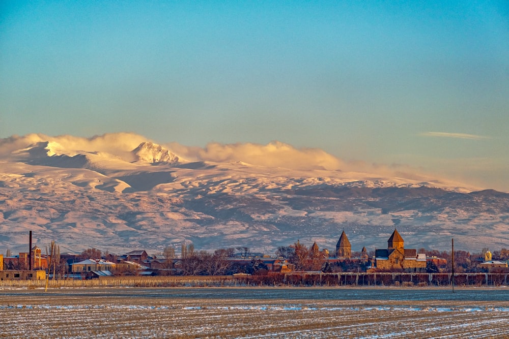 a snowy mountain range in the distance with a town in the foreground