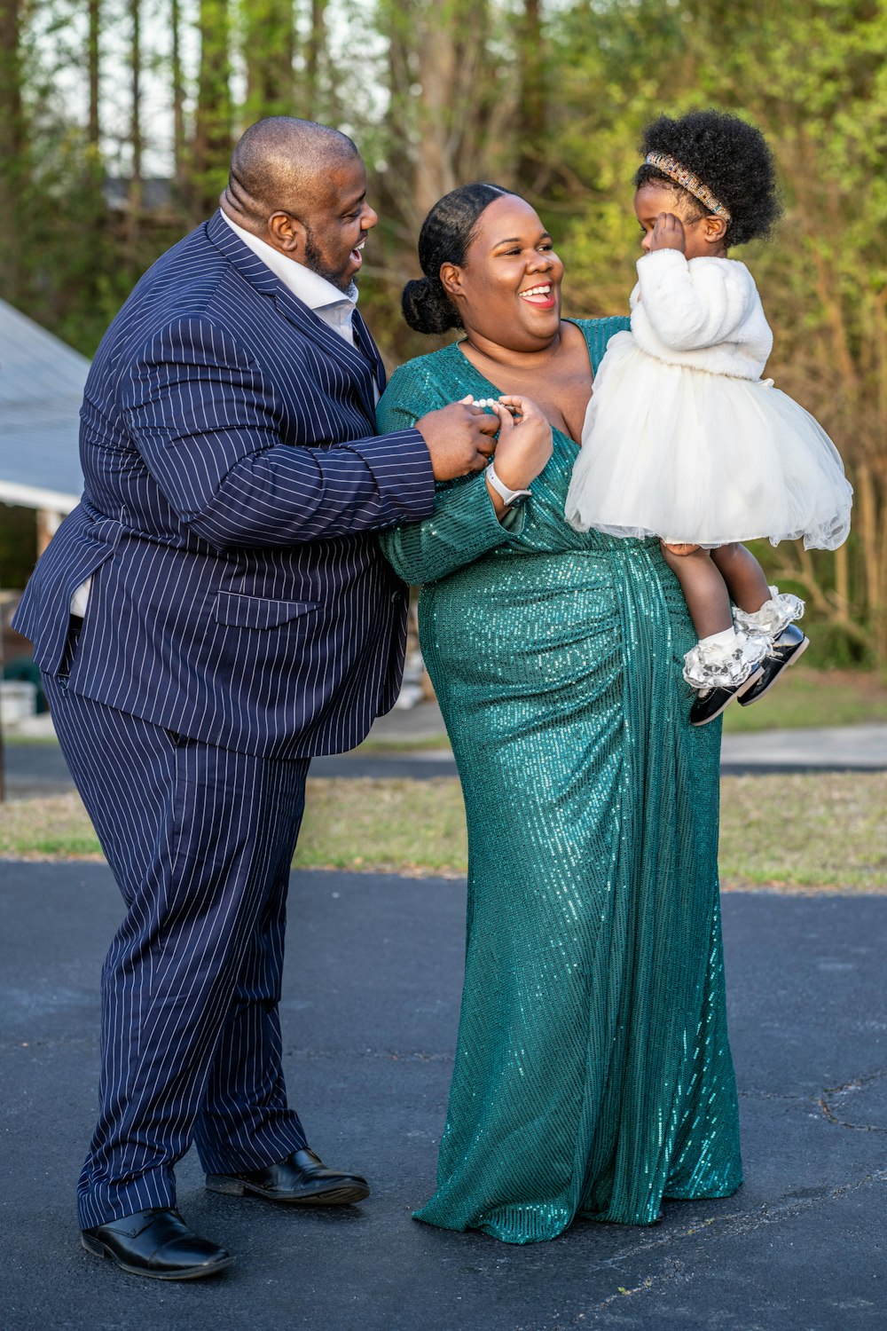a woman in a green dress holding a baby and a man in a blue suit