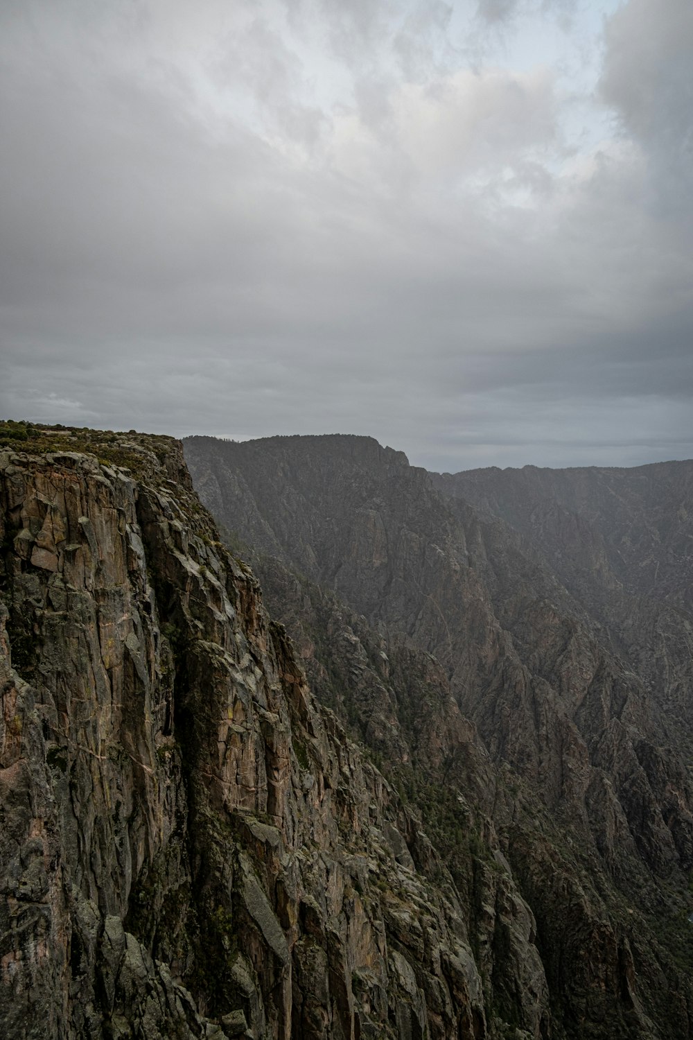 a man standing on top of a mountain next to a cliff