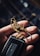 A hand is holding a set of keys. The focus is on a detailed metal keychain shaped like a mechanical insect or grasshopper. The keychain is intricately designed with metallic accents. The keys attached include a modern car key with a sleek black design.