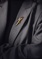 Close-up of a golden lapel pin on a classic black suit jacket.