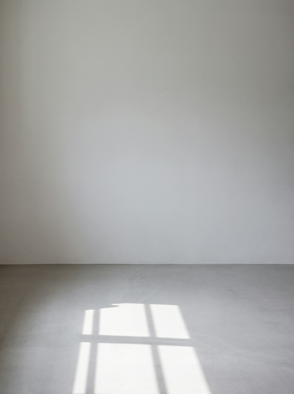 an empty room with a white wall and a window