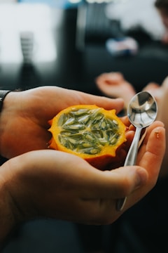 A close-up of hands holding a heart-shaped fruit.