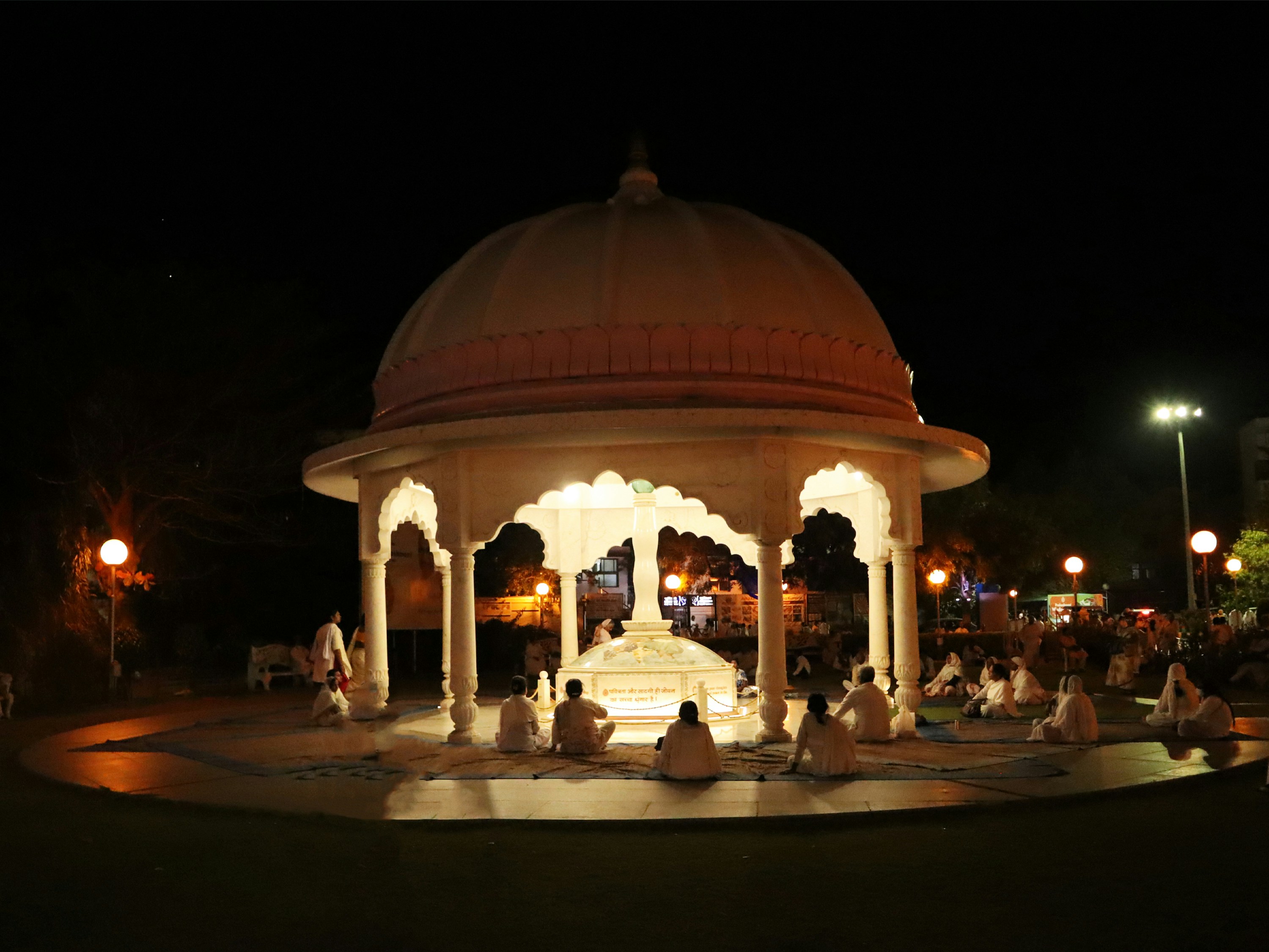 a group of people sitting around a white gazebo