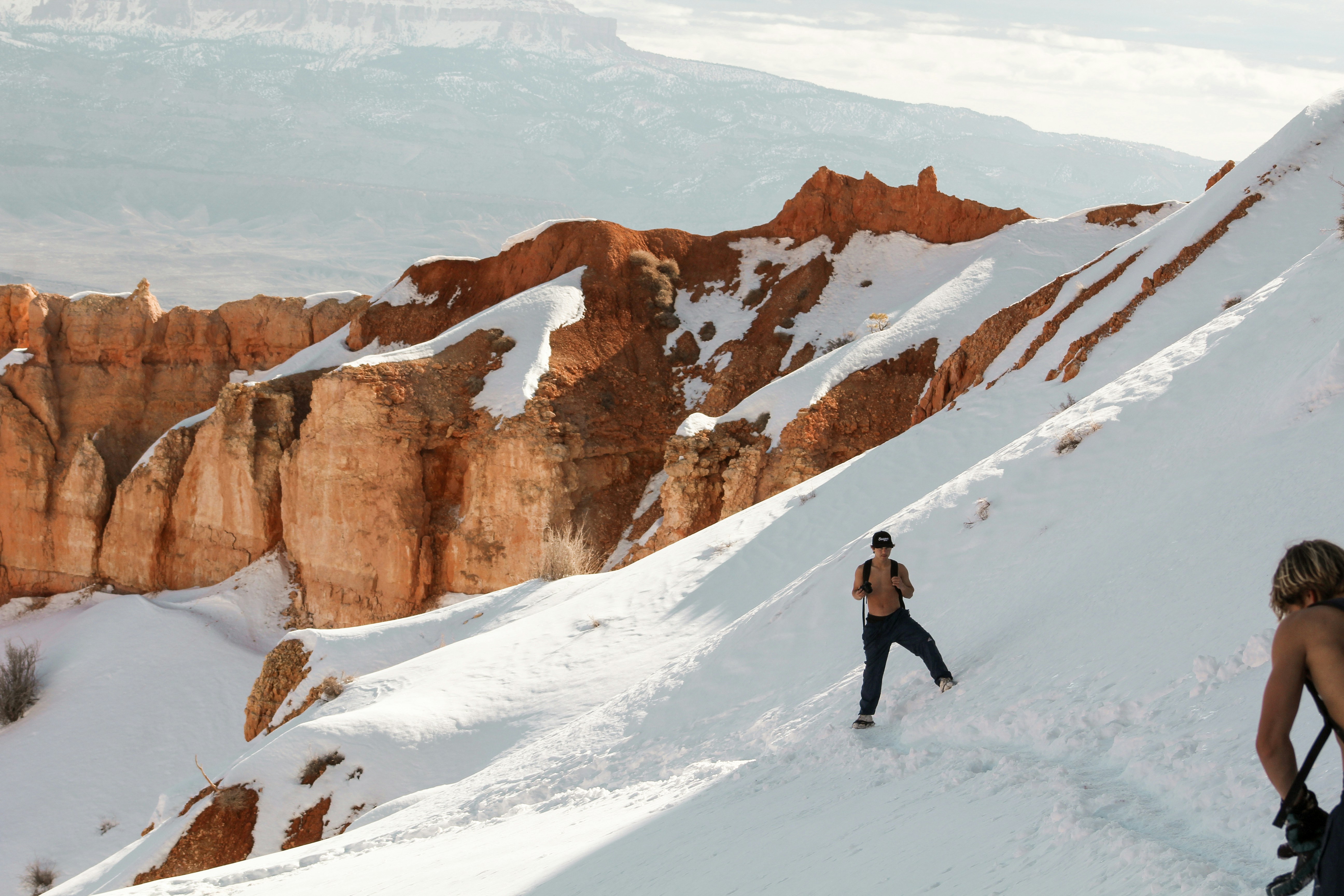 Un uomo che cammina sul fianco di una montagna coperta di neve
