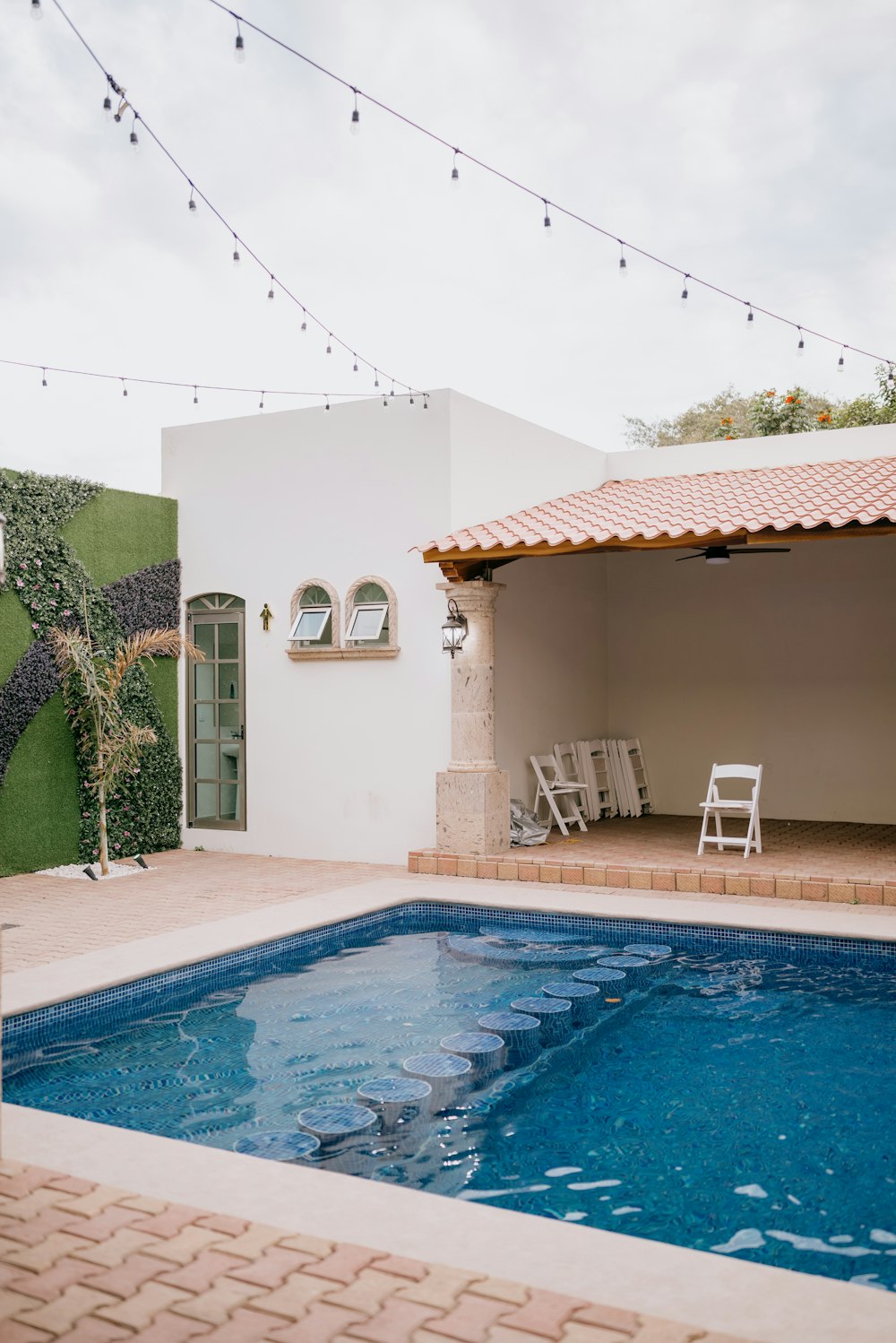 a swimming pool with a tiled patio and patio furniture