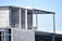 An unfinished building under construction with visible concrete blocks and steel beams. The structure appears to be at an early stage with some parts exposed and not yet completed. There are electrical conduits and reinforcement rods visible.