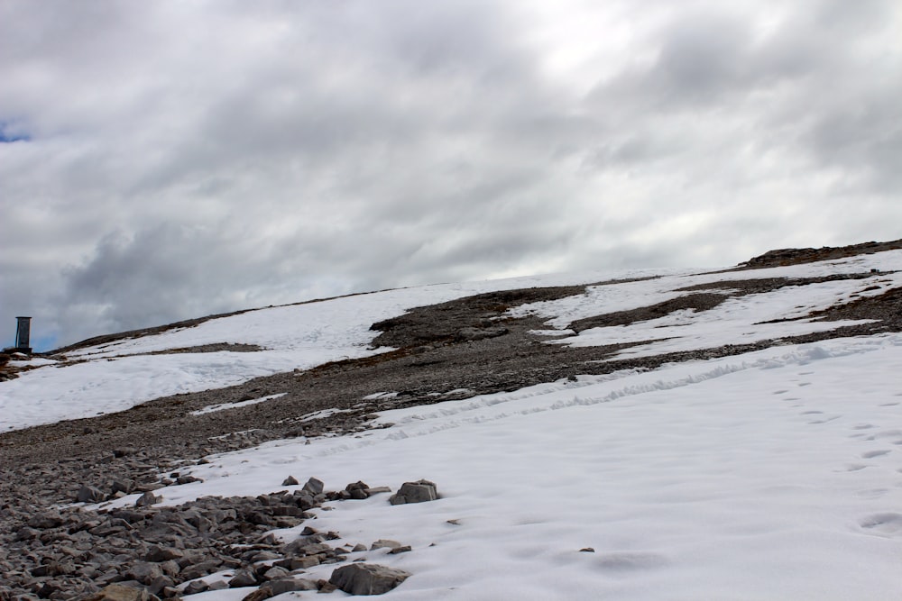 a snow covered hill with rocks and a light house in the distance