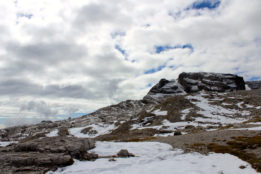 a rocky mountain with snow on the ground