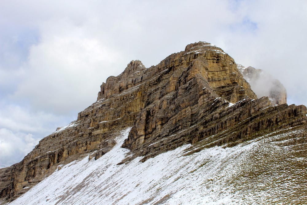 a mountain covered in snow with a cloud in the sky