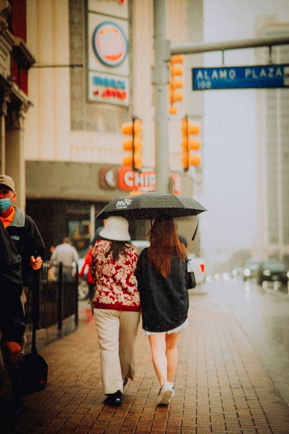 two people walking down a sidewalk with an umbrella