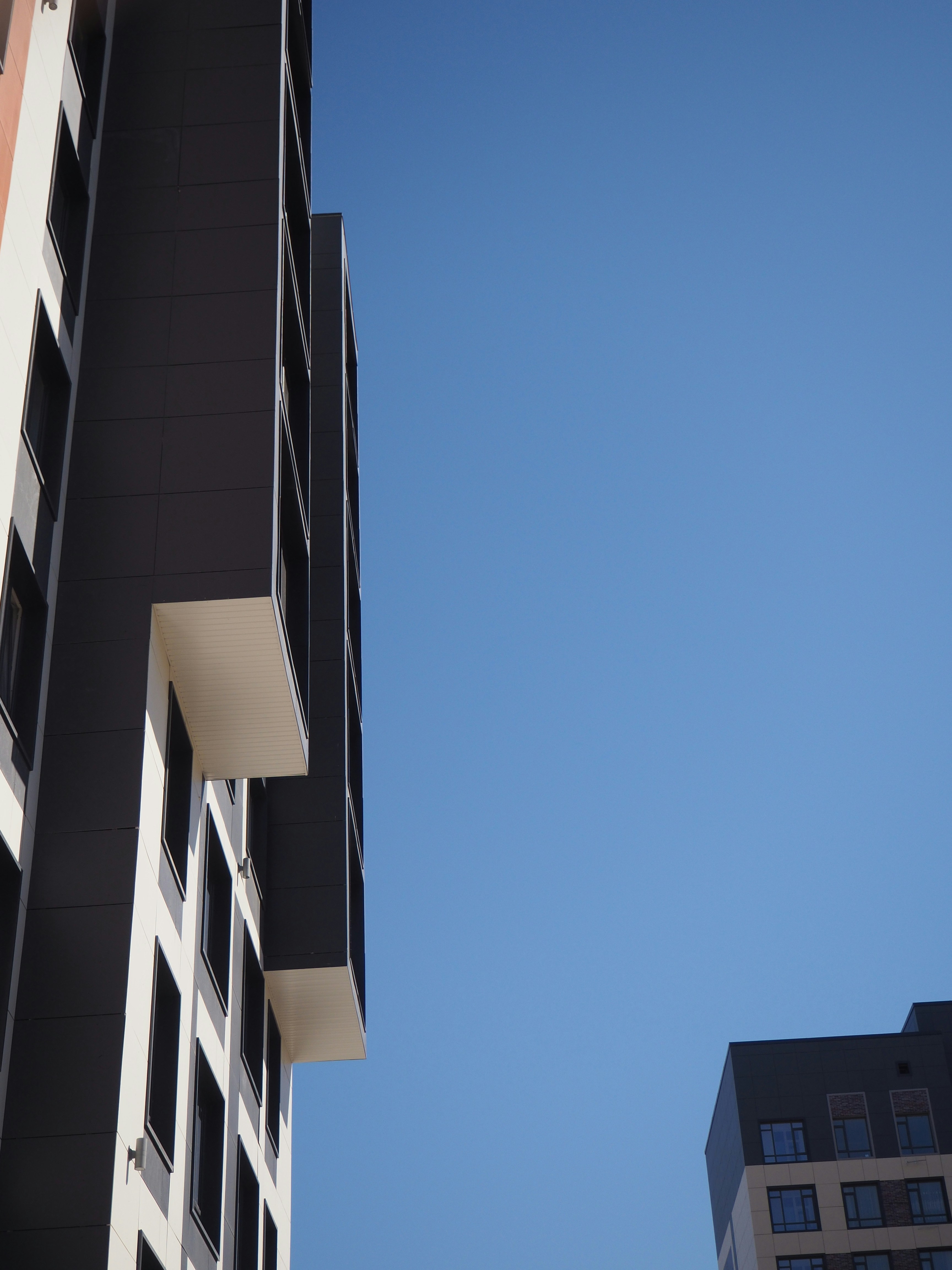 two tall buildings with balconies against a blue sky