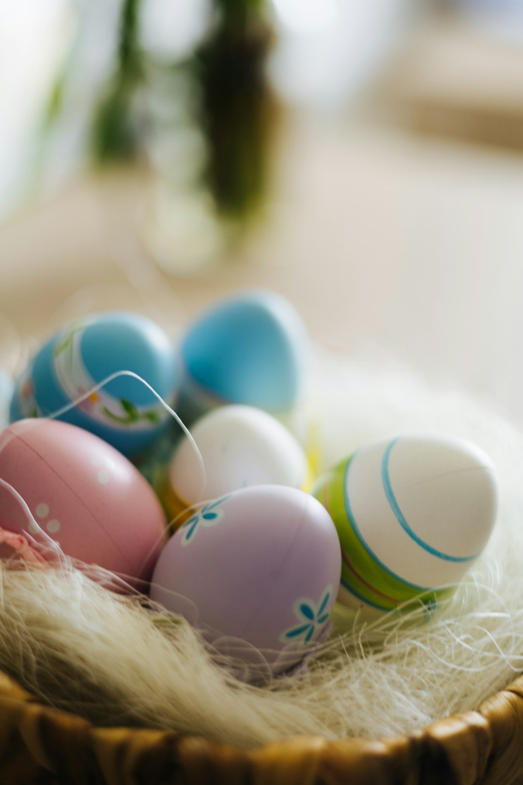 a basket filled with colorful eggs on top of a table