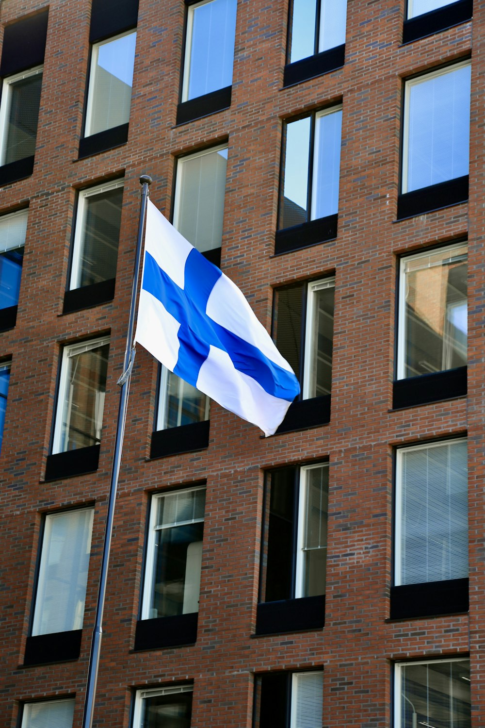 a blue and white flag flying in front of a brick building