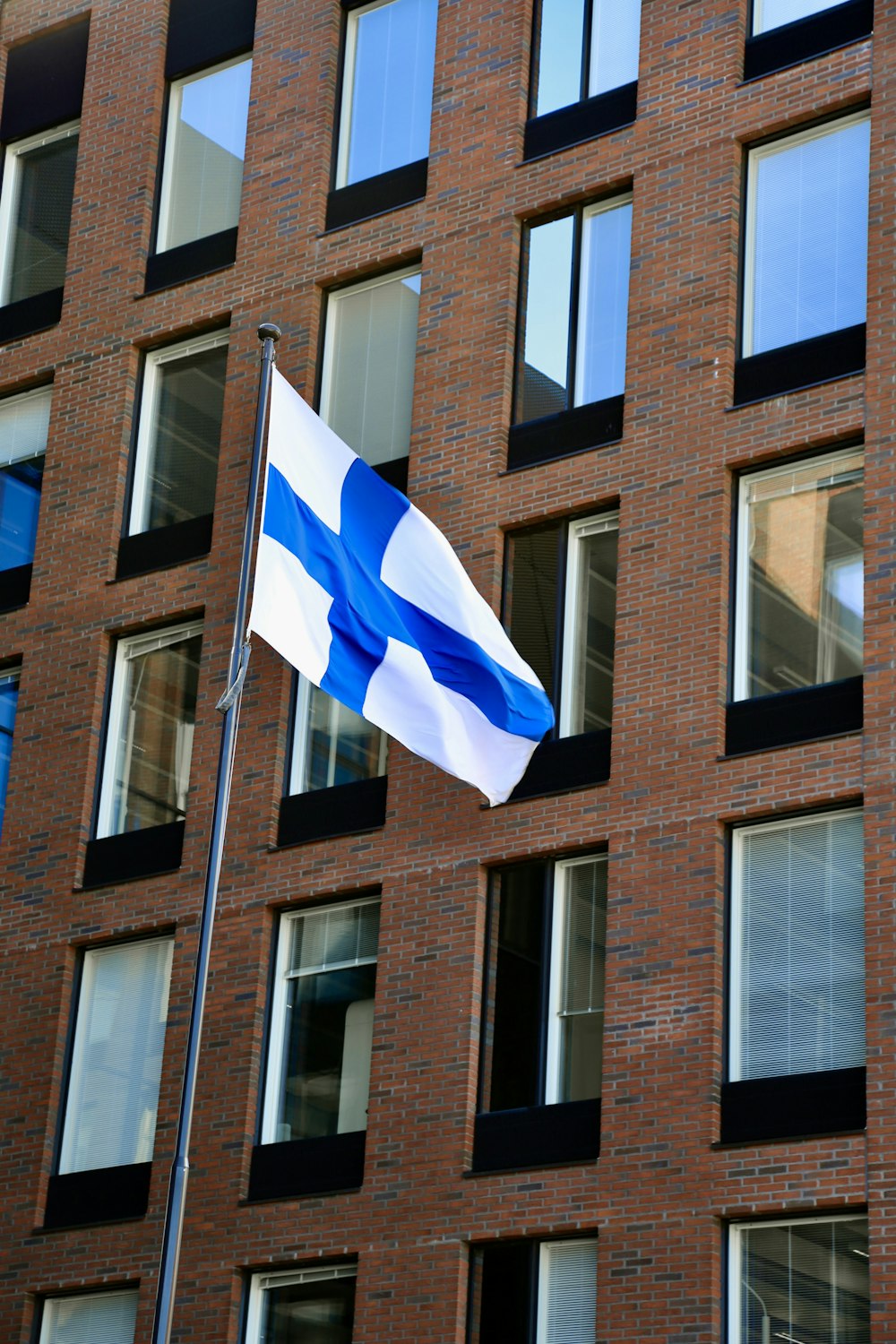 Un drapeau bleu et blanc flottant devant un bâtiment en briques