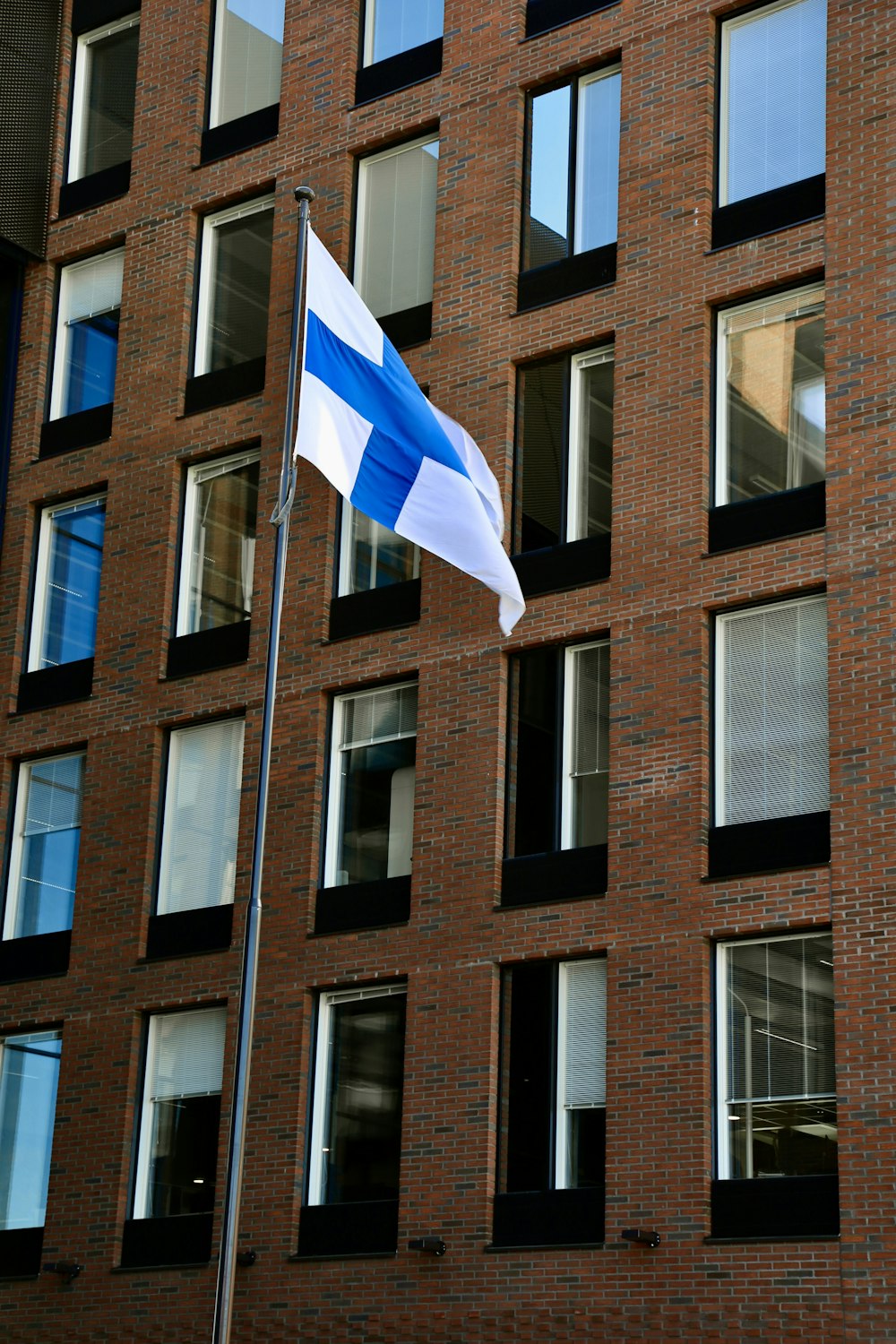 a blue and white flag flying in front of a brick building