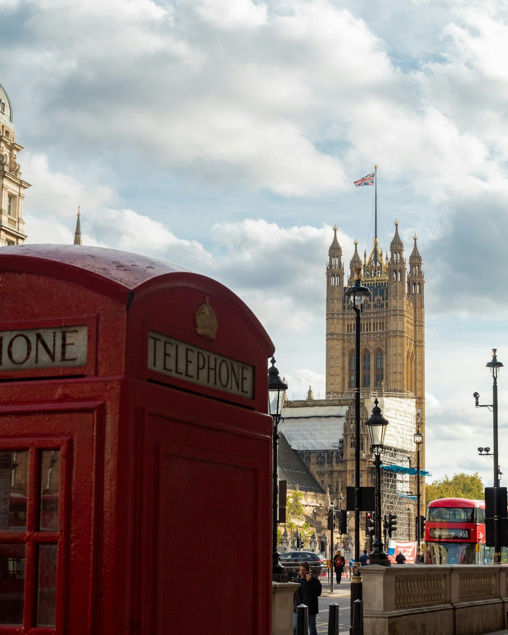 a red telephone booth sitting on the side of a road