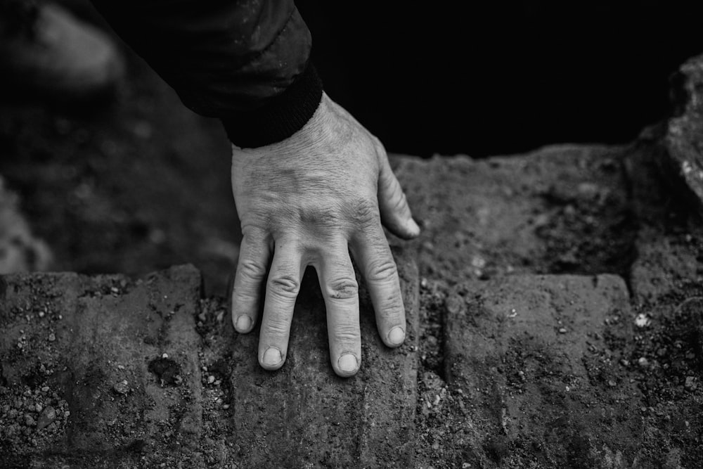 a person's hand resting on a rock