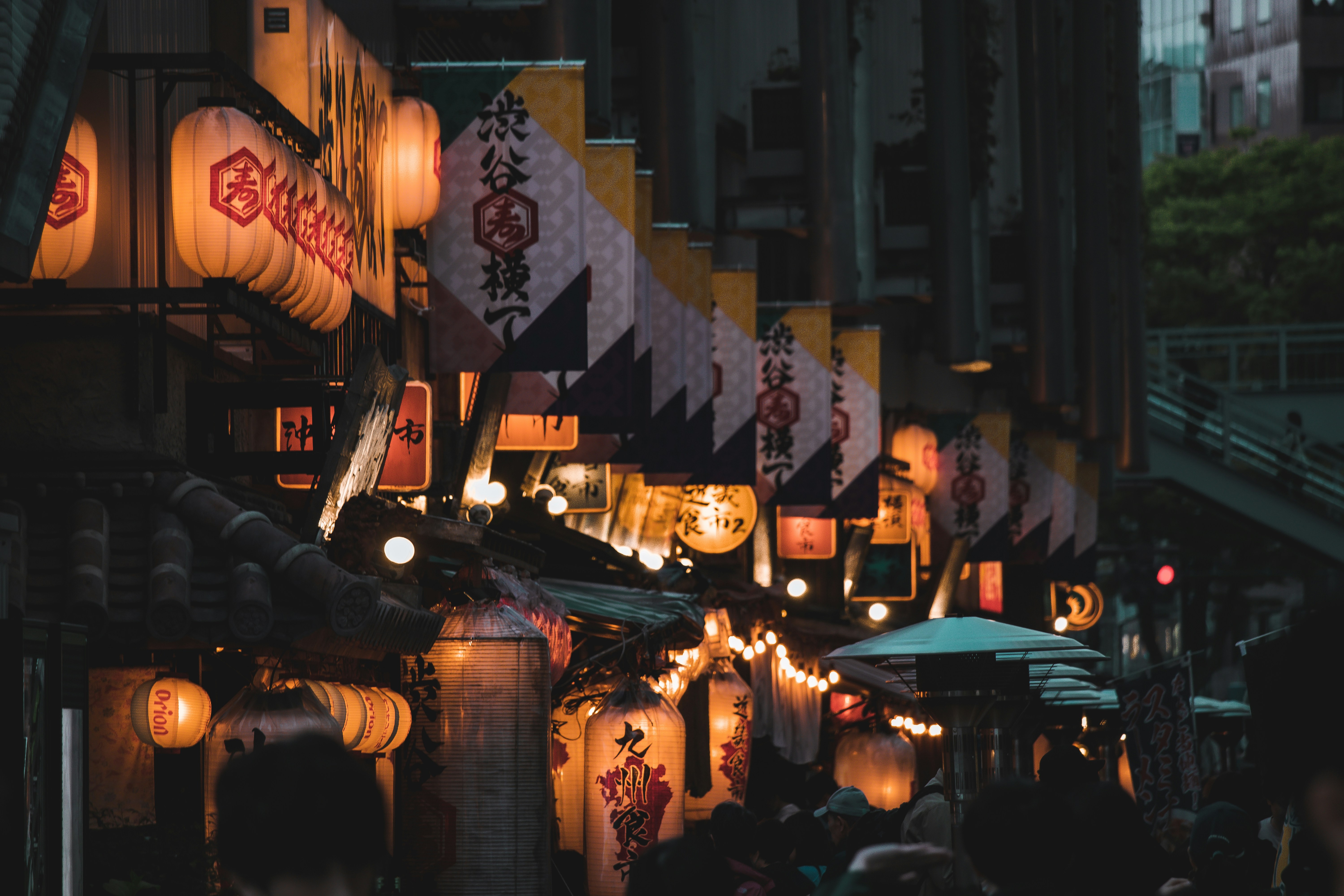 Vibrant Japanese food market at sunset with glowing lanterns illuminating colourful produce stalls