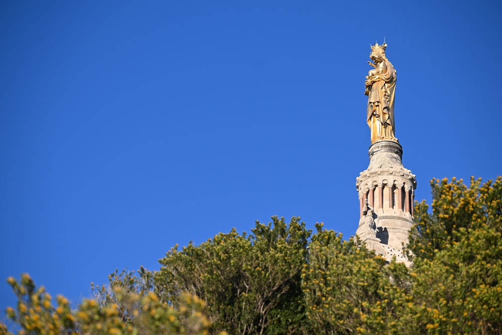 a statue on top of a building surrounded by trees