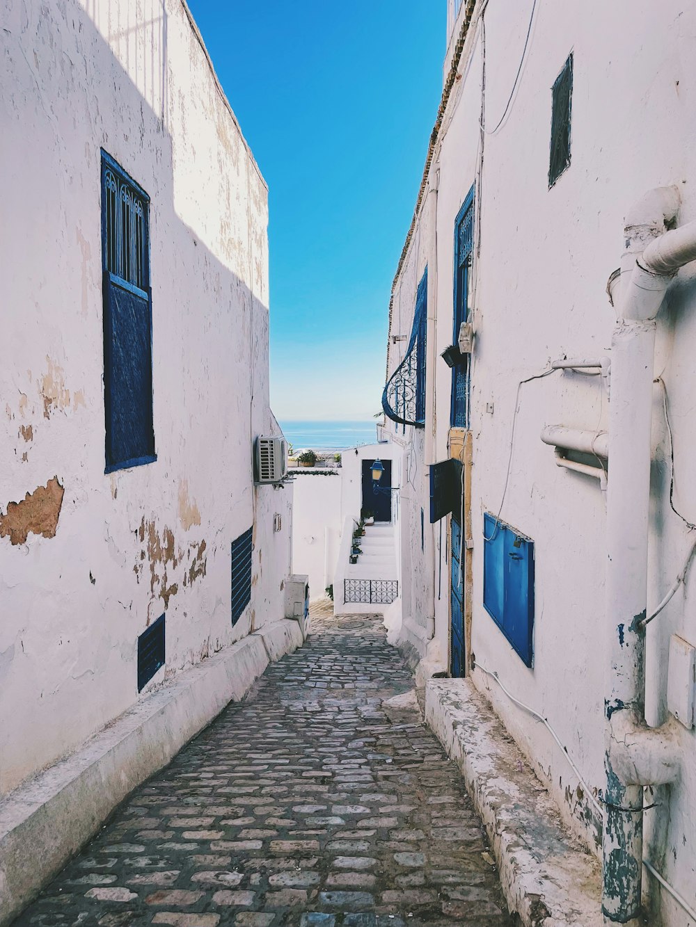 a narrow cobblestone street with blue windows