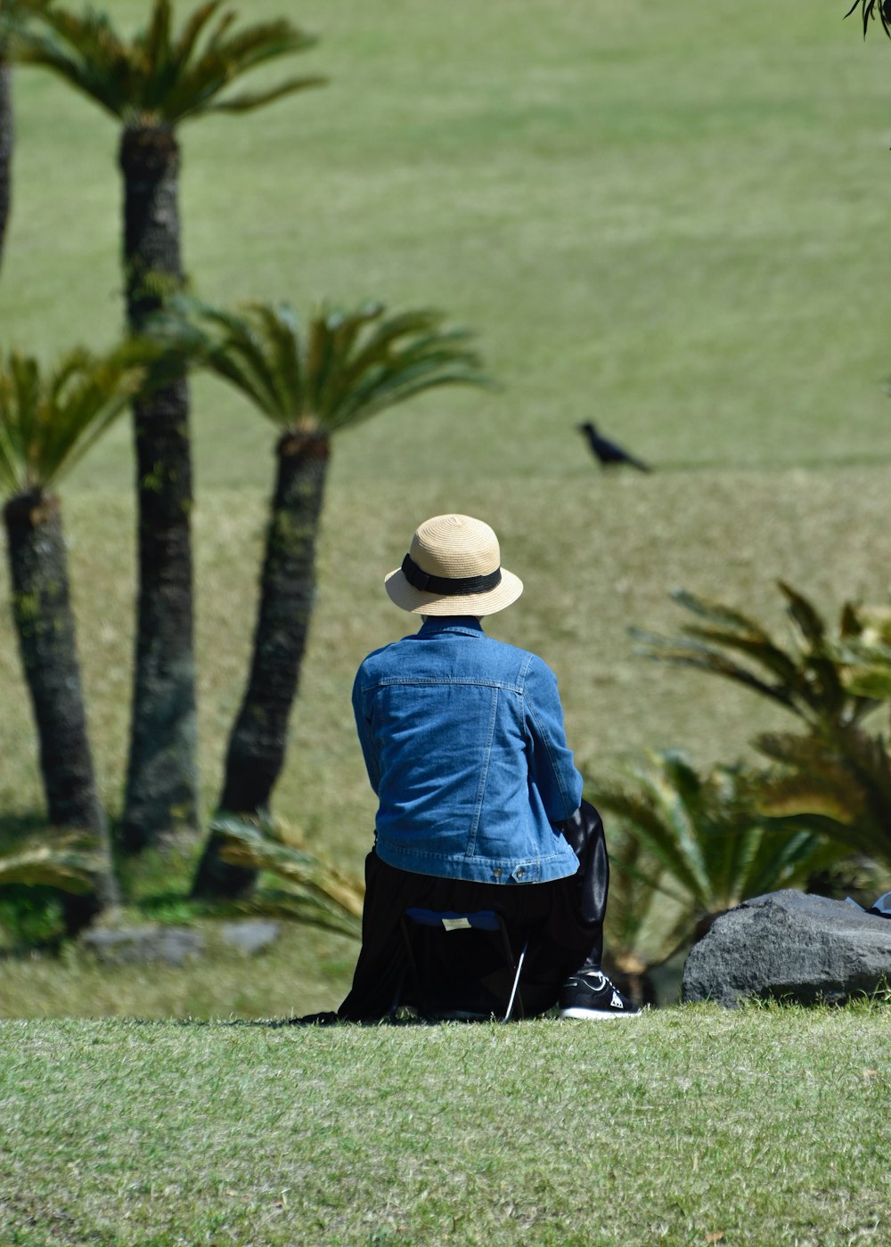 a person sitting on the grass with a hat on