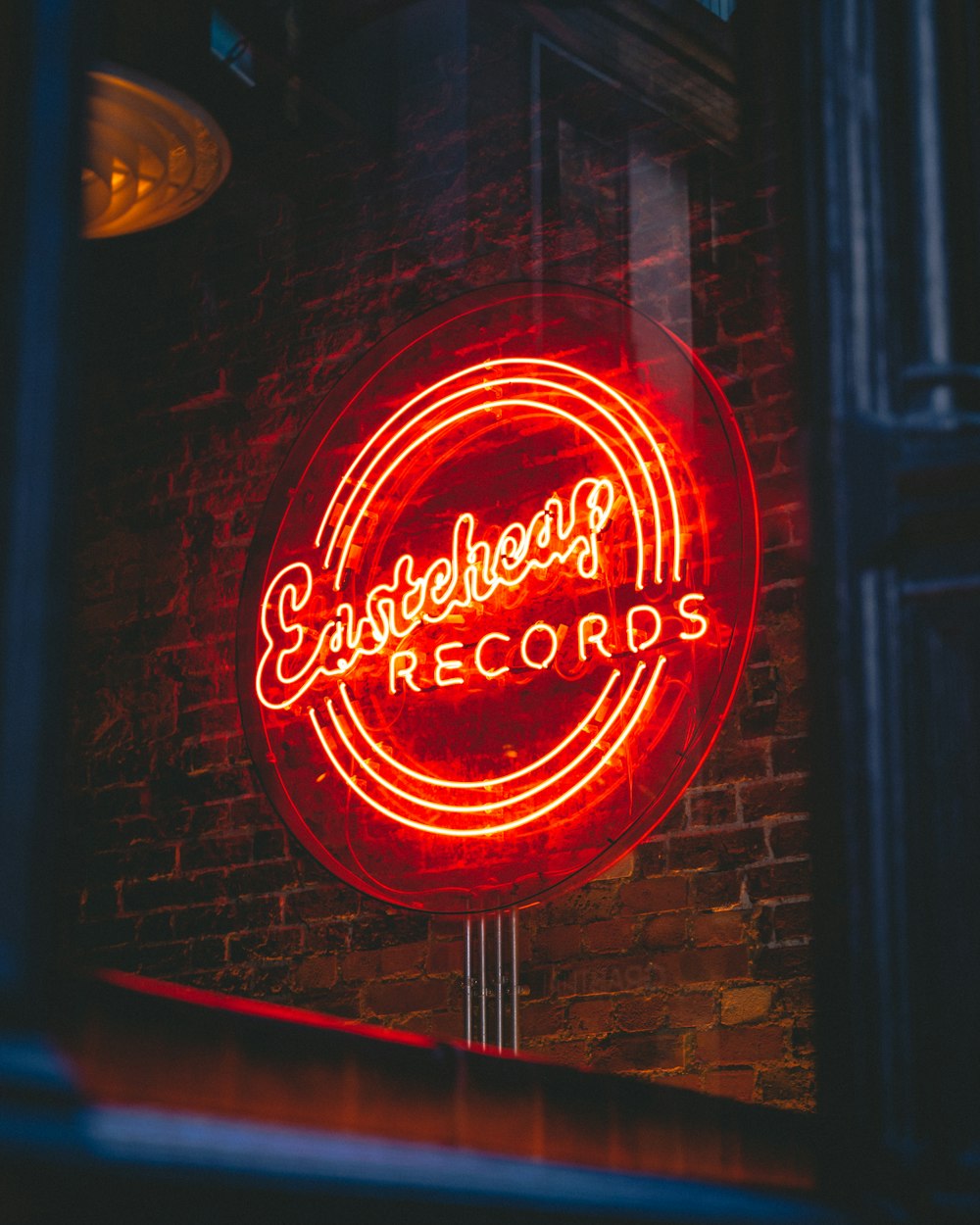 a neon sign on a brick wall advertising a record store