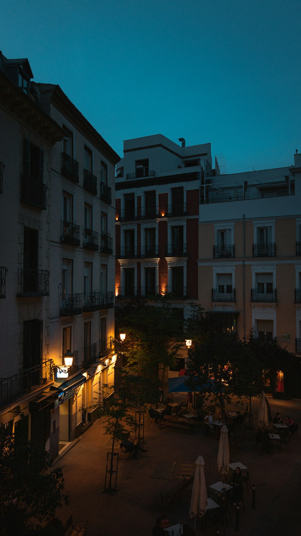 a courtyard with tables and chairs lit up at night