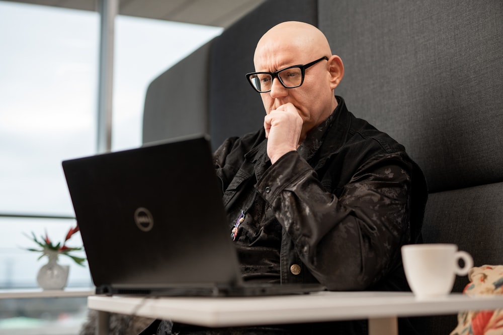 Ein kahlköpfiger Mann sitzt vor einem Laptop