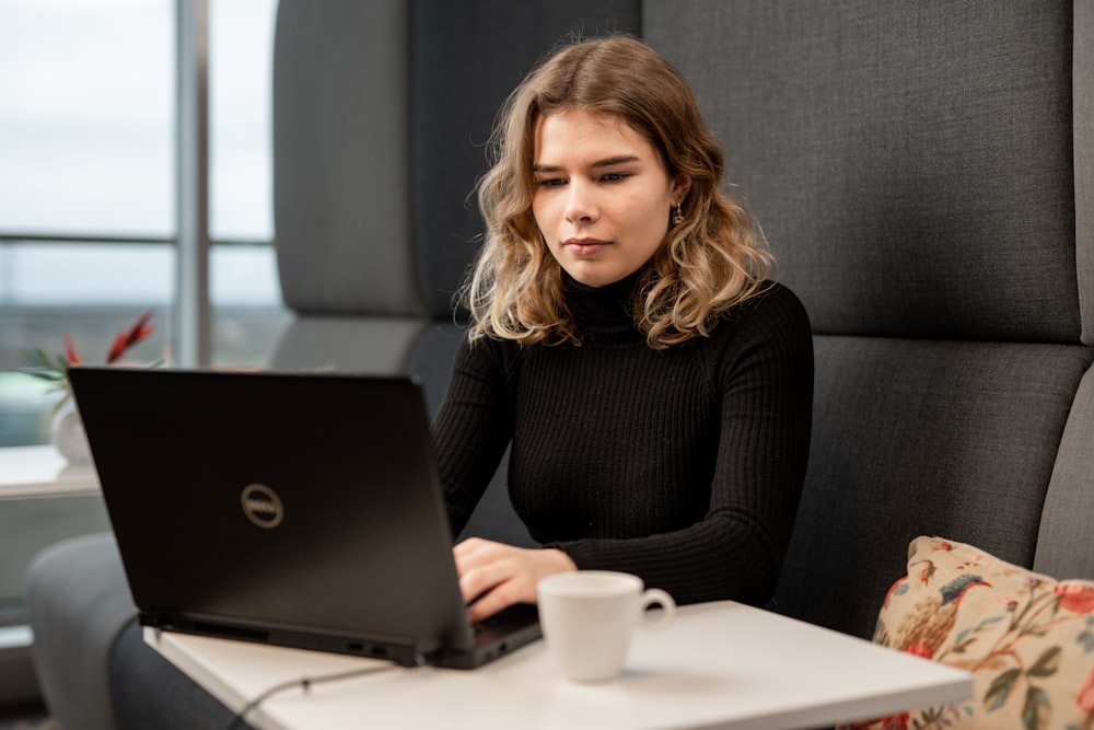 Eine Frau sitzt mit einem Laptop an einem Tisch