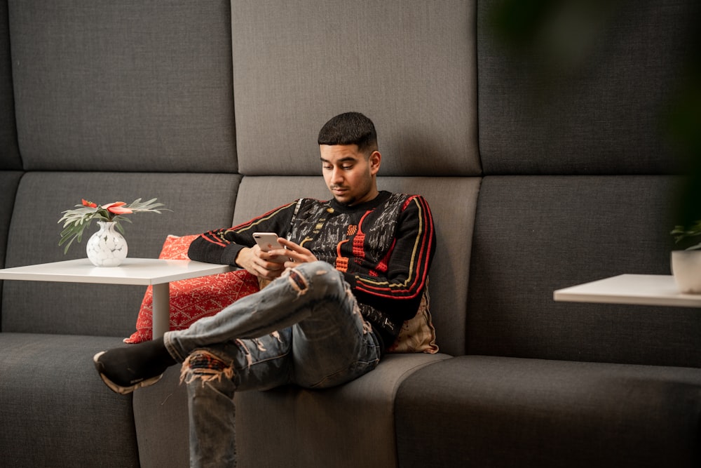 a man sitting on a couch looking at his cell phone