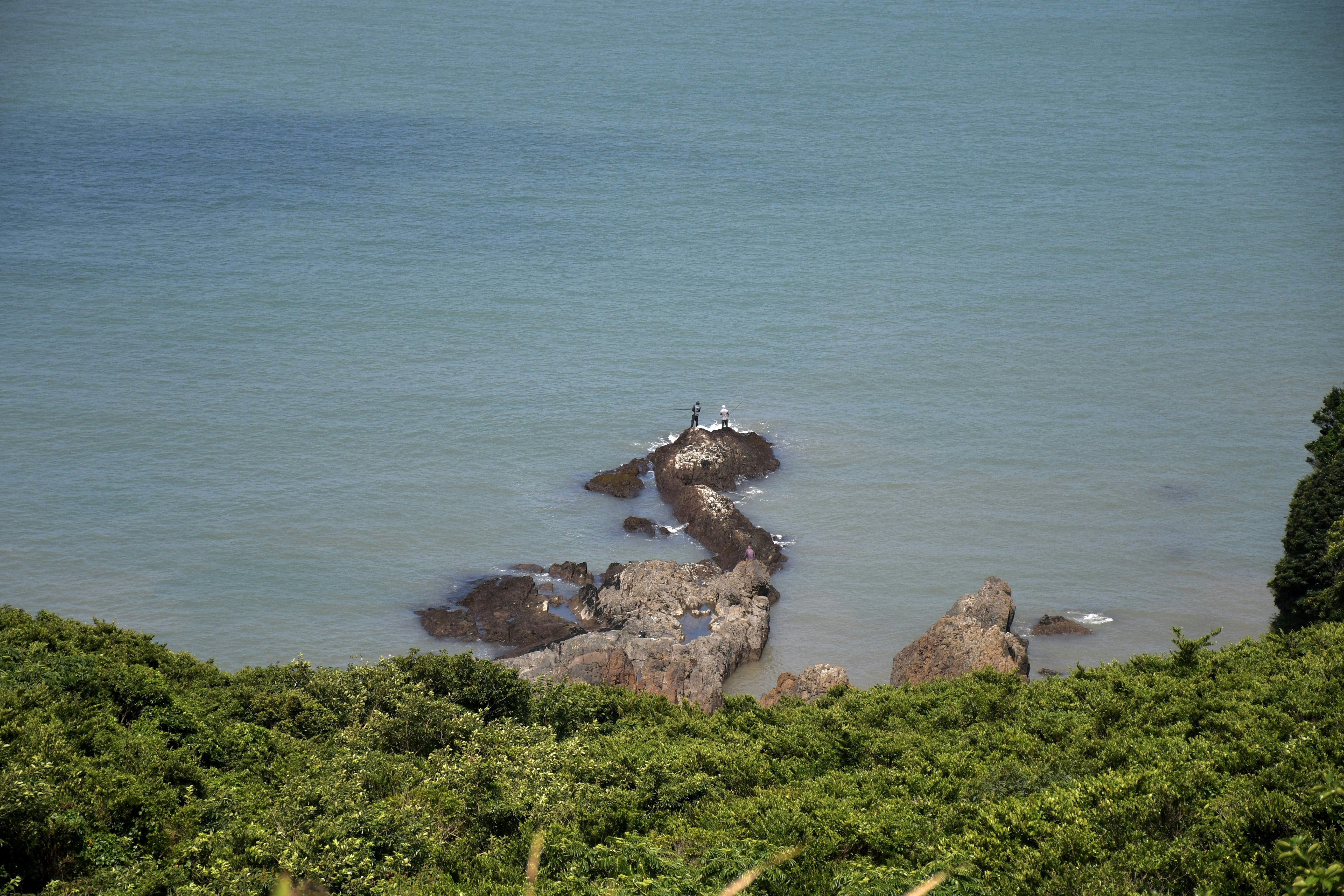 a group of rocks sitting on top of a lush green hillside
