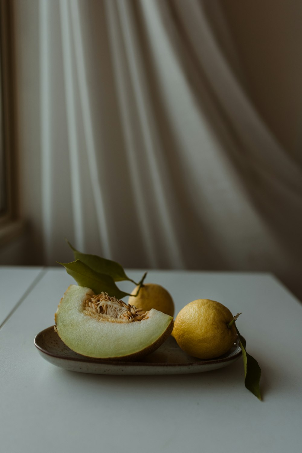 a plate of fruit on a table next to a window