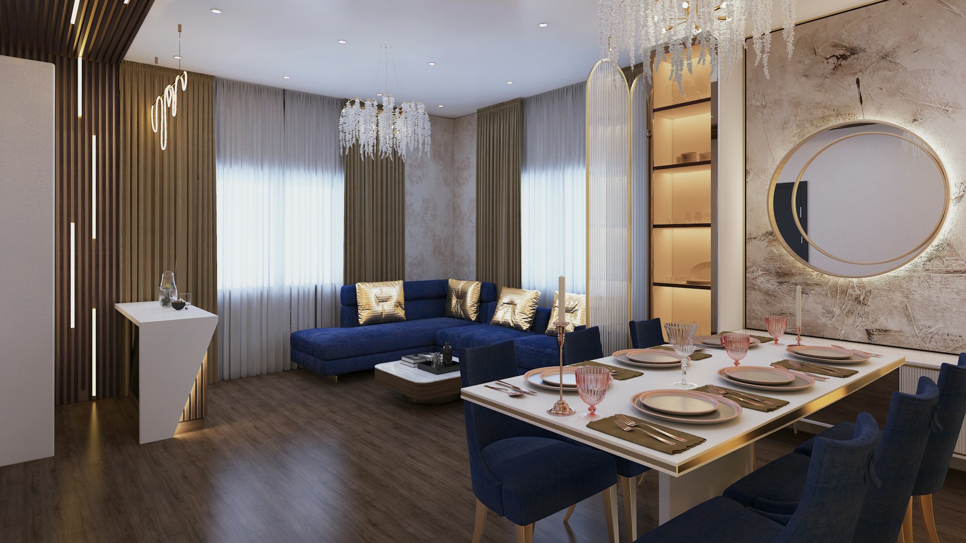 A modern living and dining area featuring a cozy corner sofa in deep blue with gold accent cushions. The dining table is elegantly set with stylish tableware and surrounded by matching blue chairs. Crystal chandeliers hang from the ceiling, adding a touch of luxury. The walls are adorned with textured paneling and a circular decorative mirror. The space is illuminated by natural light filtering through sheer curtains.