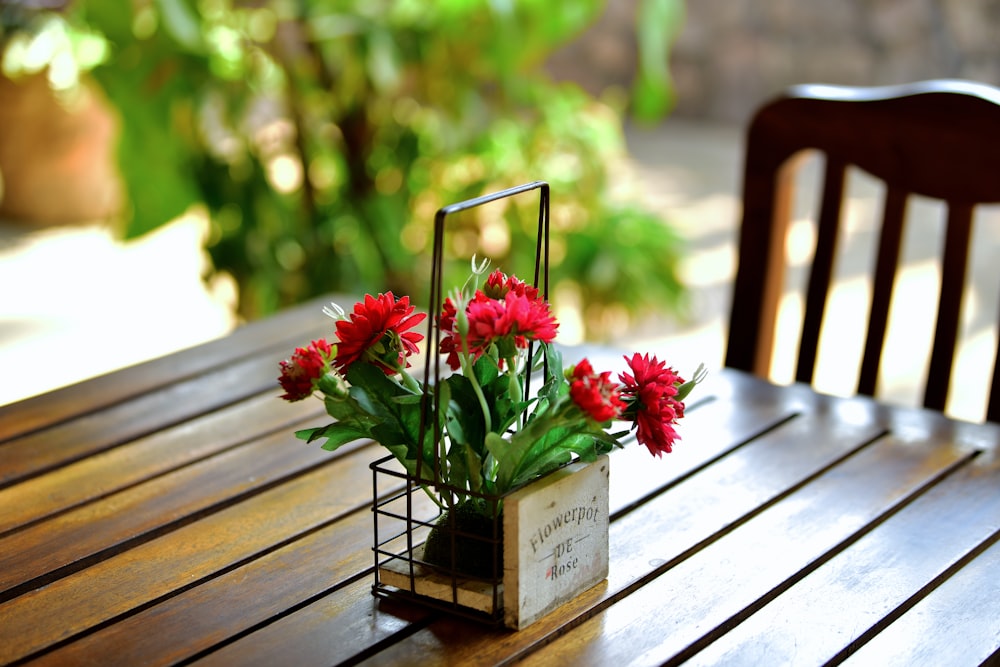 a wooden table topped with a vase filled with red flowers