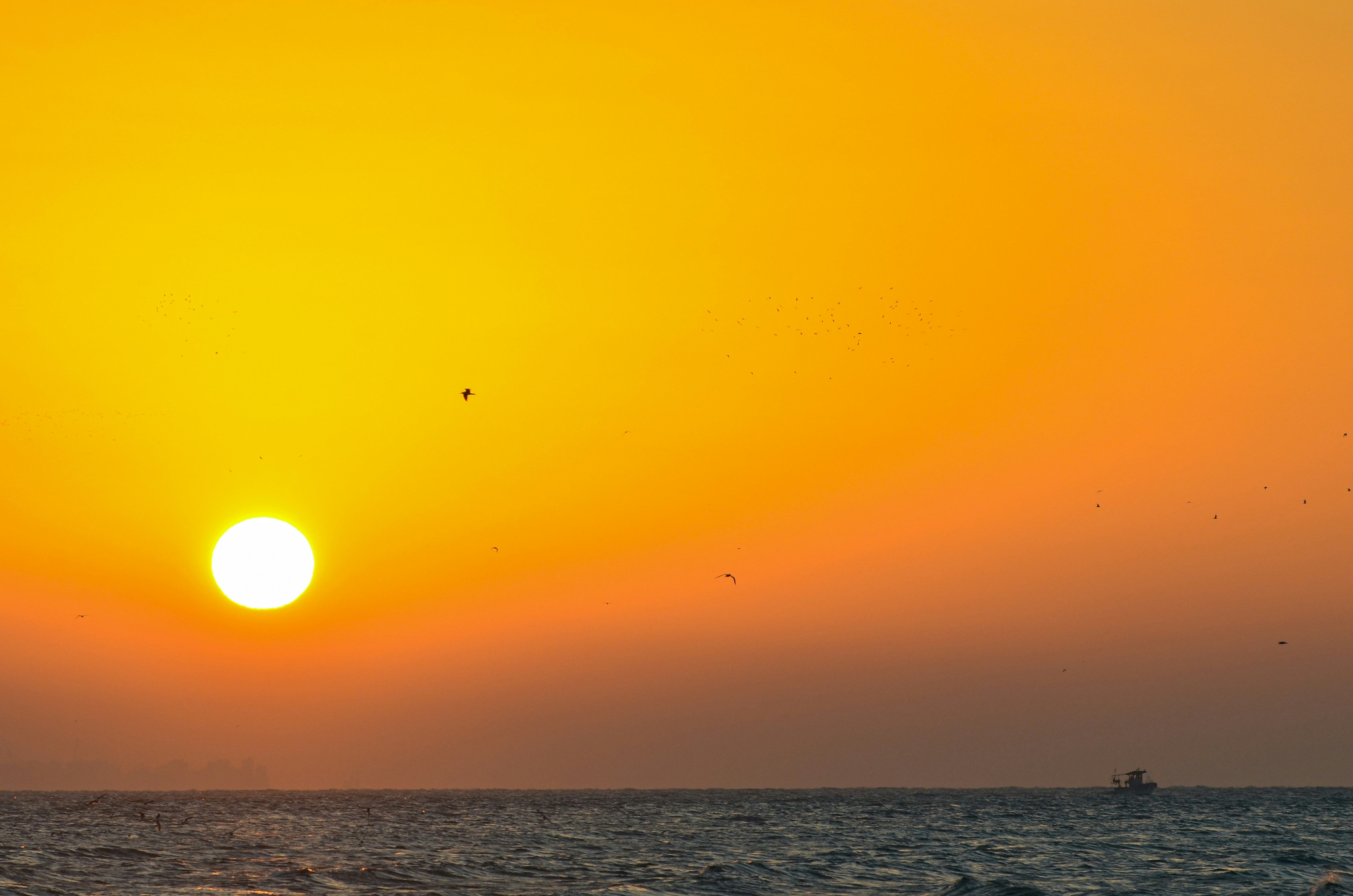 the sun is setting over the ocean with a boat in the distance, 