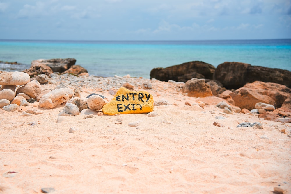 ein gelbes Schild mit der Aufschrift "Eingang Ausgang am Strand"