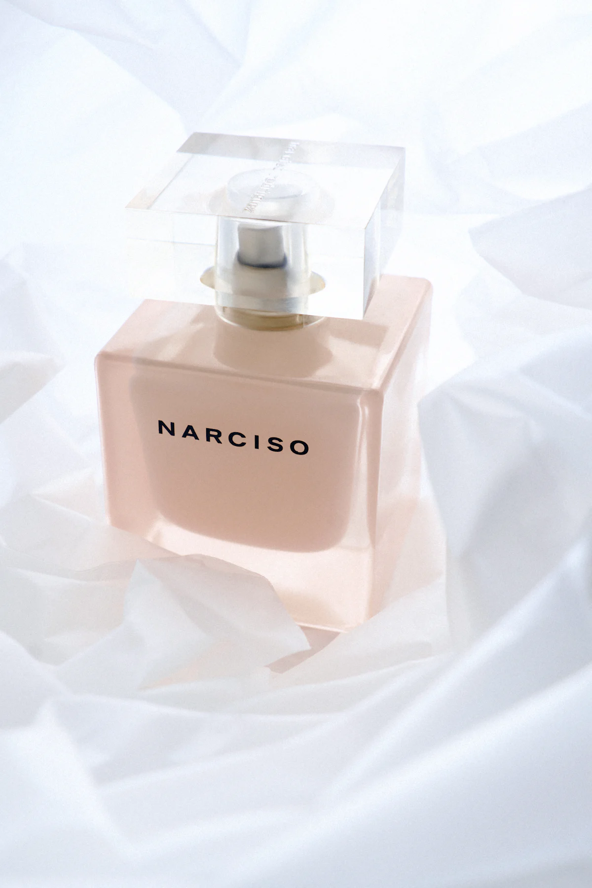 Frasco de perfume duradero sobre sábana blanca