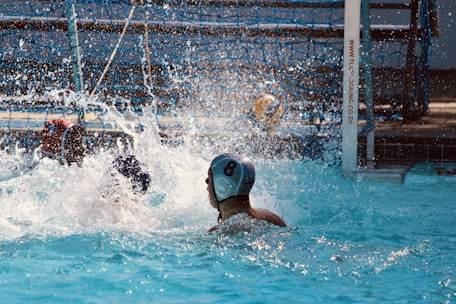 A focused water polo player making a powerful shot during a match.