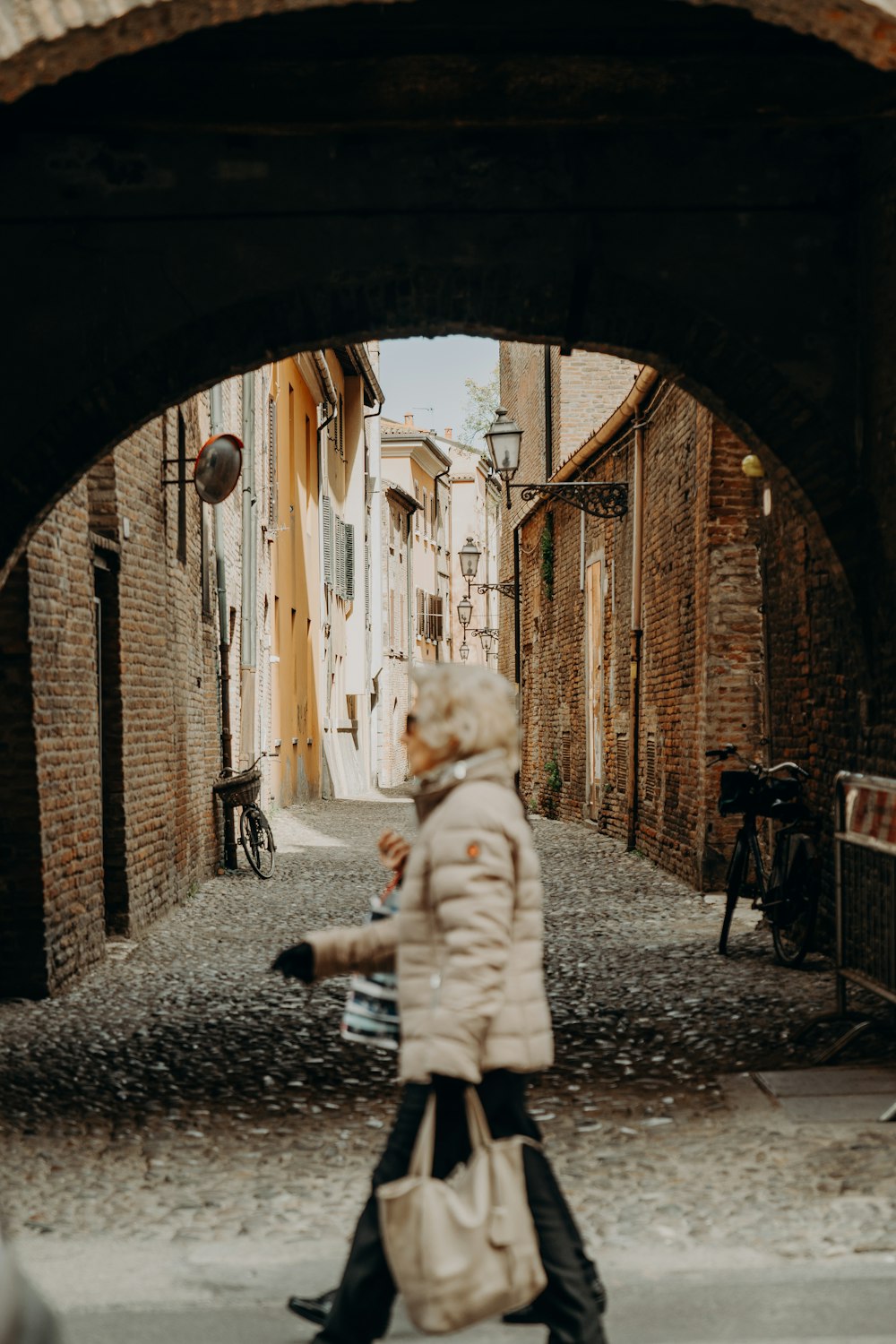 a woman walking down a street under a bridge