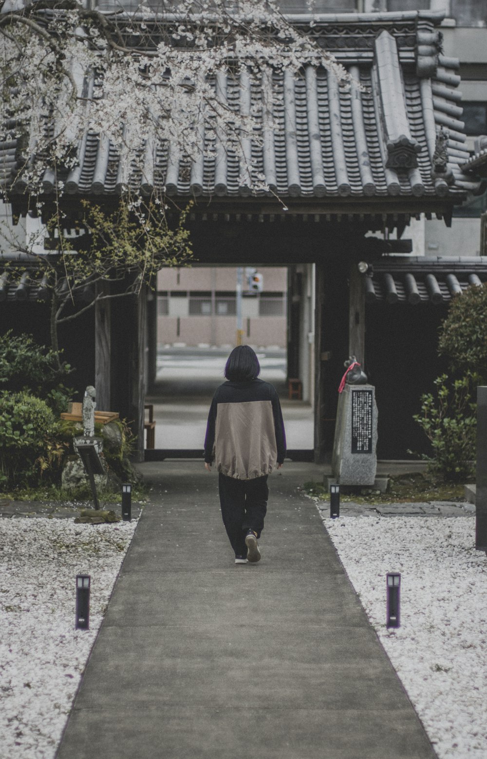 a person walking down a walkway in front of a building