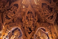 Intricately carved wooden interior featuring detailed figures and ornate patterns, reminiscent of traditional Eastern art and architecture. The craftsmanship showcases complex motifs and human-like figures interwoven with decorative elements.