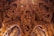 Intricately carved wooden interior featuring detailed figures and ornate patterns, reminiscent of traditional Eastern art and architecture. The craftsmanship showcases complex motifs and human-like figures interwoven with decorative elements.