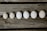 Six eggs are arranged in a line on a rustic wooden surface, showing a gradient of sizes.