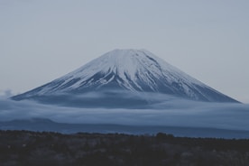 a snow covered mountain with low clouds in the foreground