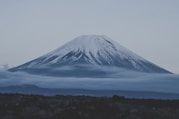 a snow covered mountain with low clouds in the foreground