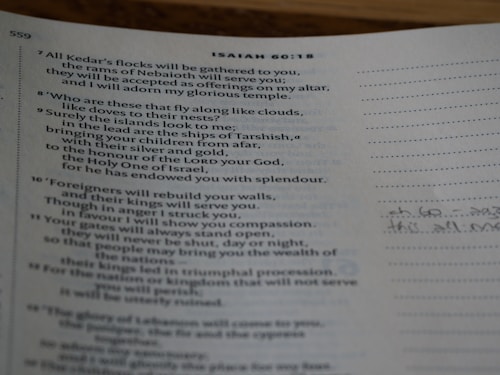 A close-up view of a page from a book, specifically a religious text, showing verses with numbers and annotations in the margin.