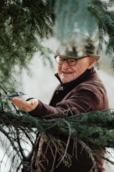 a man holding a pair of scissors in a pine tree
