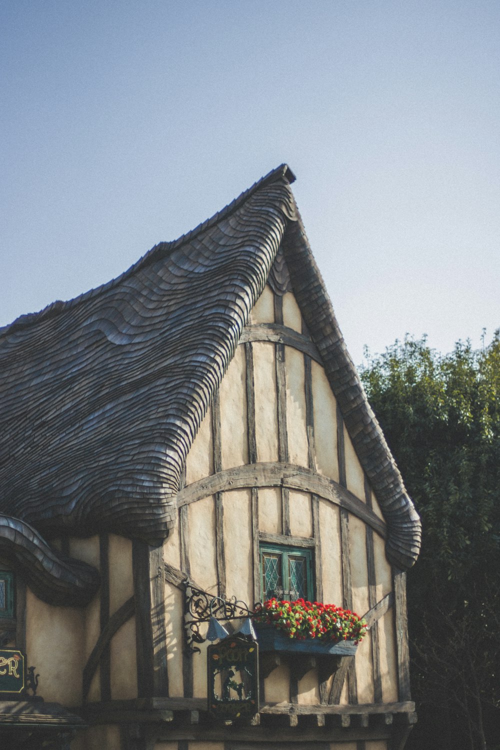 a house with a thatched roof and flowers in the window