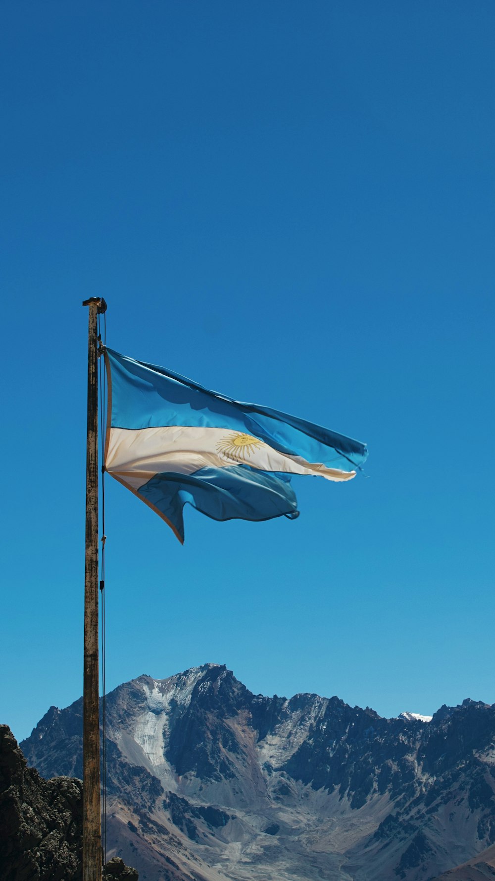 a blue and white flag flying over a mountain range